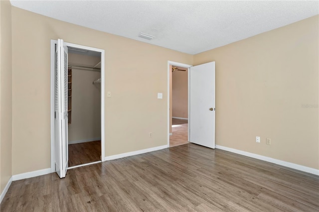 unfurnished bedroom featuring a textured ceiling, hardwood / wood-style flooring, and a closet