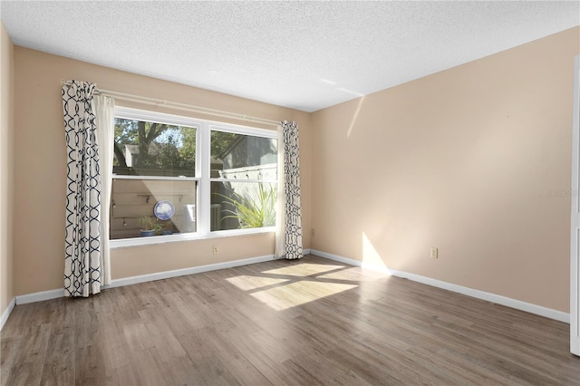 empty room featuring a textured ceiling and light hardwood / wood-style floors