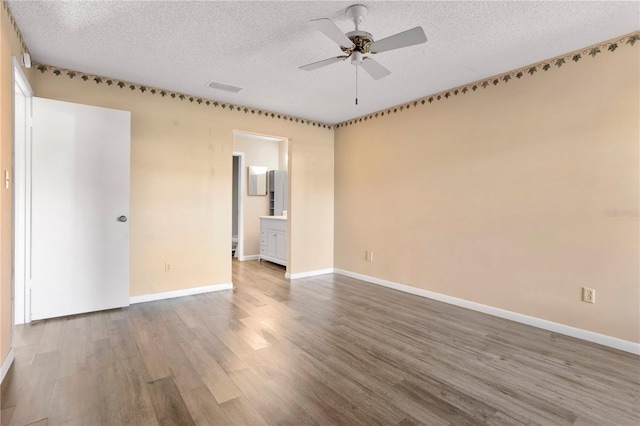 empty room with ceiling fan, a textured ceiling, and hardwood / wood-style flooring