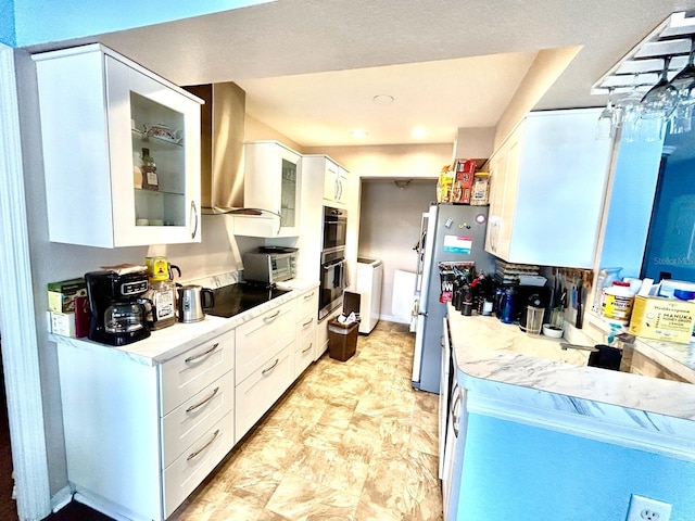 kitchen with wall chimney exhaust hood, black appliances, white cabinets, and washing machine and dryer