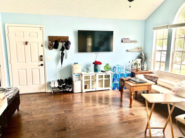 living room with lofted ceiling, dark wood-type flooring, a textured ceiling, and ceiling fan