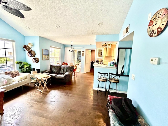 living room featuring vaulted ceiling, a textured ceiling, and ceiling fan with notable chandelier