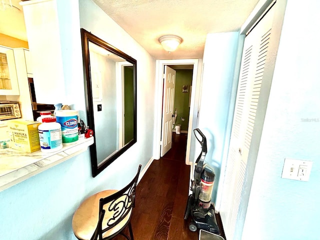 corridor with a textured ceiling and dark hardwood / wood-style flooring