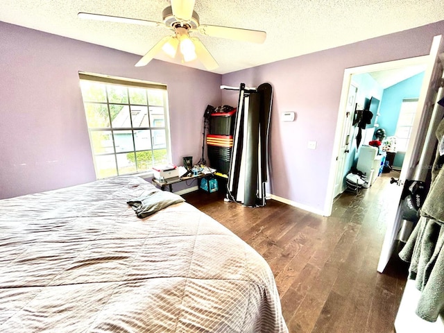 bedroom with dark hardwood / wood-style flooring, ceiling fan, a textured ceiling, a barn door, and vaulted ceiling