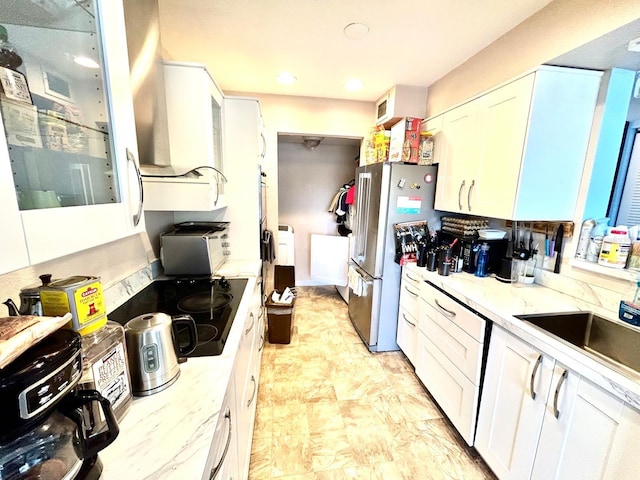 kitchen featuring white cabinets, sink, and stainless steel refrigerator