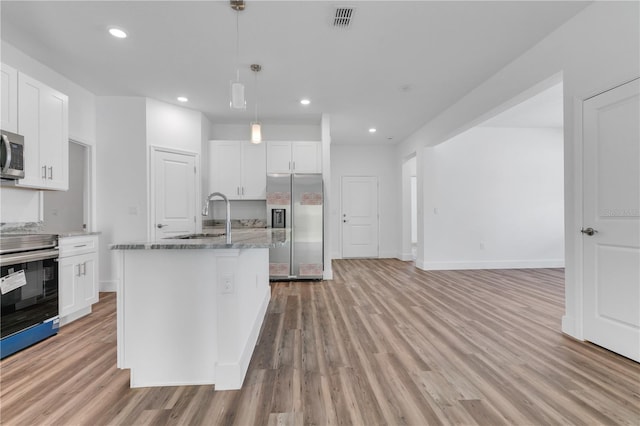 kitchen with a center island with sink, appliances with stainless steel finishes, white cabinets, and light hardwood / wood-style floors