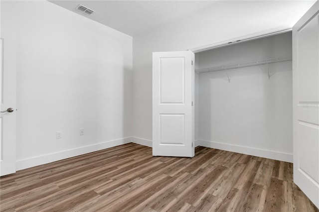 unfurnished bedroom featuring a textured ceiling, wood-type flooring, and a closet