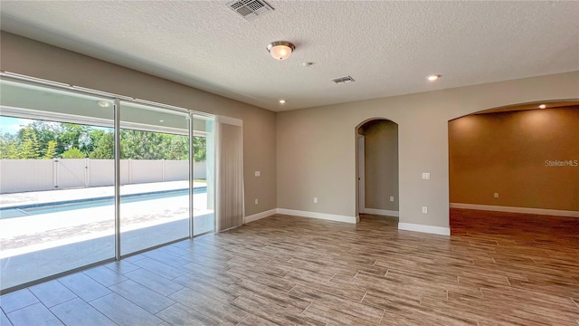 empty room featuring a textured ceiling and hardwood / wood-style floors