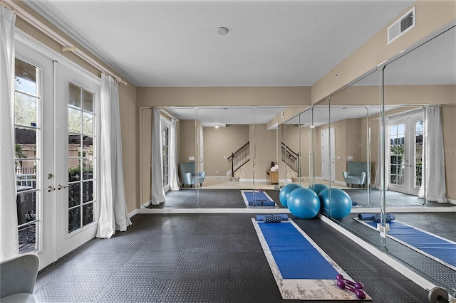 workout room featuring french doors, a textured ceiling, track lighting, and a wealth of natural light