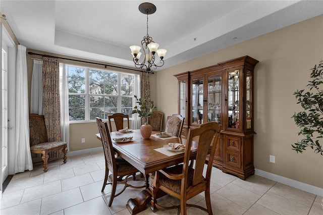 dining room with an inviting chandelier, a raised ceiling, and light tile patterned floors