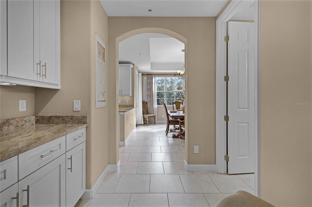 hallway with light tile patterned flooring and a chandelier