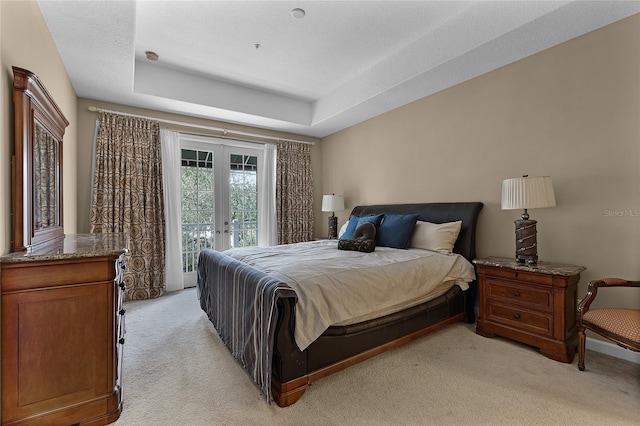 carpeted bedroom with french doors, a textured ceiling, access to exterior, and a raised ceiling