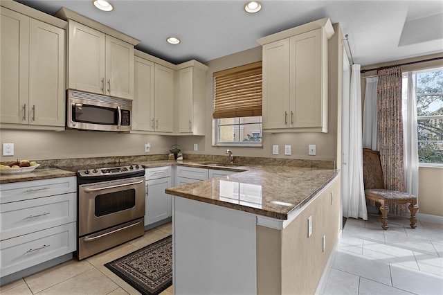 kitchen featuring stone counters, sink, appliances with stainless steel finishes, and light tile patterned floors