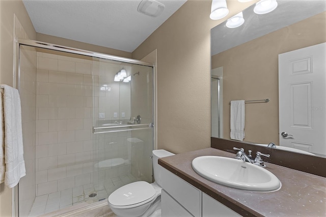 bathroom featuring toilet, a textured ceiling, walk in shower, and vanity