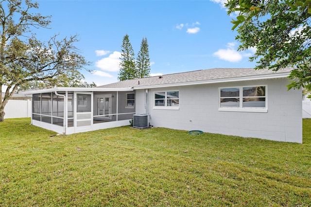 rear view of property featuring central AC unit, a lawn, and a sunroom