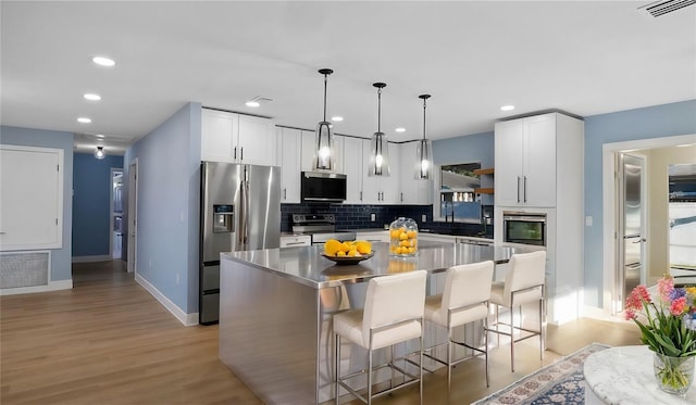 kitchen featuring stainless steel appliances, a breakfast bar, a kitchen island, and white cabinets