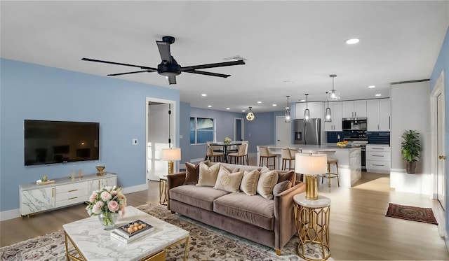 living room featuring ceiling fan and light hardwood / wood-style floors