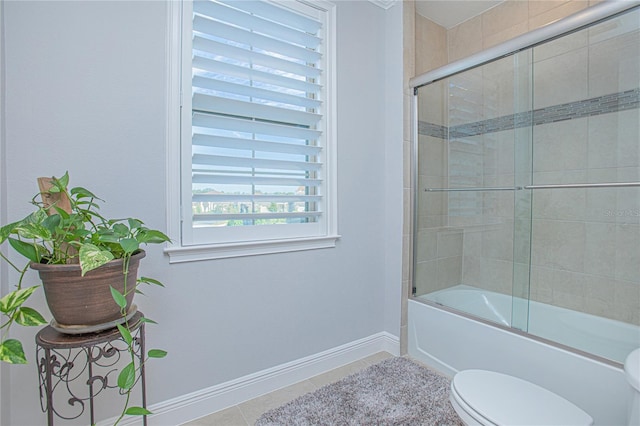 bathroom featuring toilet, tile patterned floors, and combined bath / shower with glass door