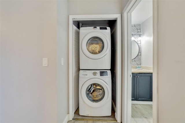 clothes washing area featuring stacked washer / drying machine and light wood-type flooring