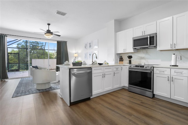 kitchen featuring kitchen peninsula, ceiling fan, appliances with stainless steel finishes, dark hardwood / wood-style flooring, and white cabinetry