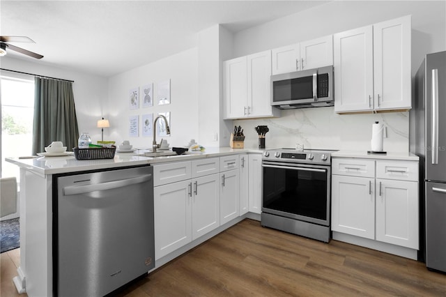 kitchen featuring white cabinets, stainless steel appliances, a ceiling fan, a sink, and a peninsula
