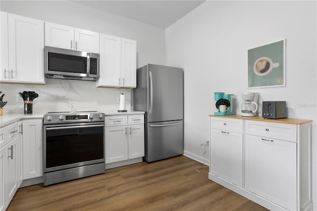 kitchen with white cabinets, baseboards, dark wood finished floors, backsplash, and appliances with stainless steel finishes