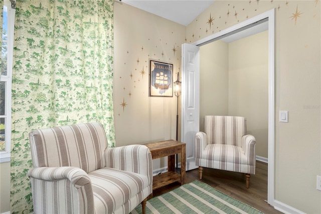 sitting room featuring baseboards, wood finished floors, and wallpapered walls