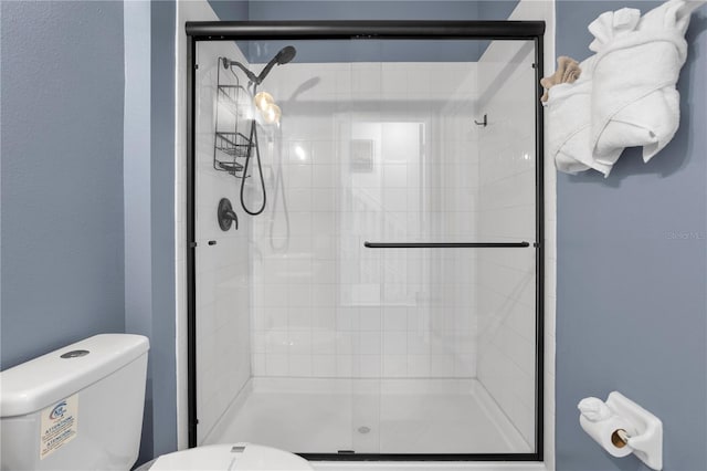 bathroom featuring a shower with shower door and toilet