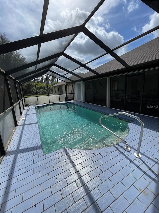 view of pool with a patio area and glass enclosure