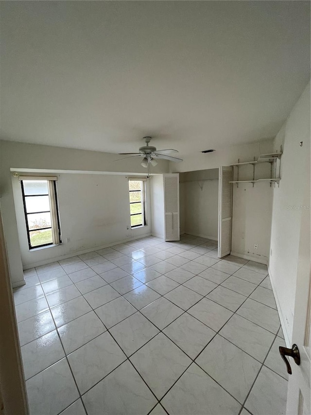 tiled spare room featuring ceiling fan and a healthy amount of sunlight