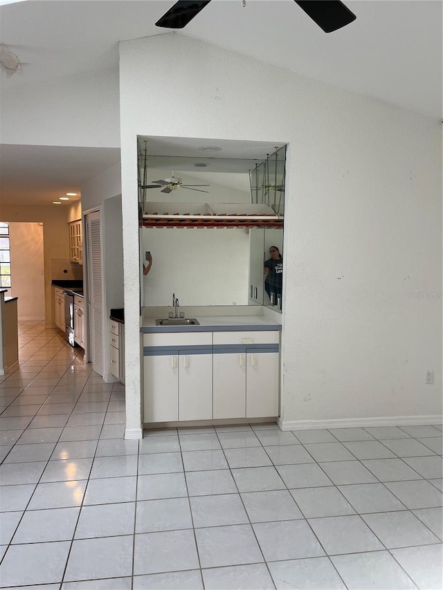 bar featuring stainless steel range, vaulted ceiling, light tile patterned flooring, white cabinetry, and ceiling fan