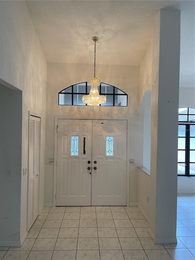 tiled entrance foyer with a towering ceiling, a textured ceiling, and a wealth of natural light