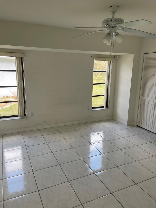 unfurnished room with ceiling fan, a healthy amount of sunlight, and light tile patterned floors