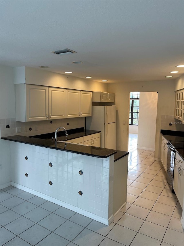 kitchen with white cabinetry, white fridge, black dishwasher, and light tile patterned floors