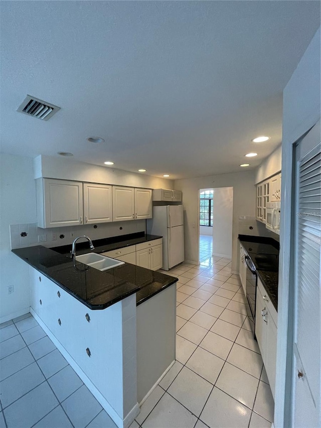 kitchen with white appliances, light tile patterned flooring, sink, kitchen peninsula, and white cabinetry