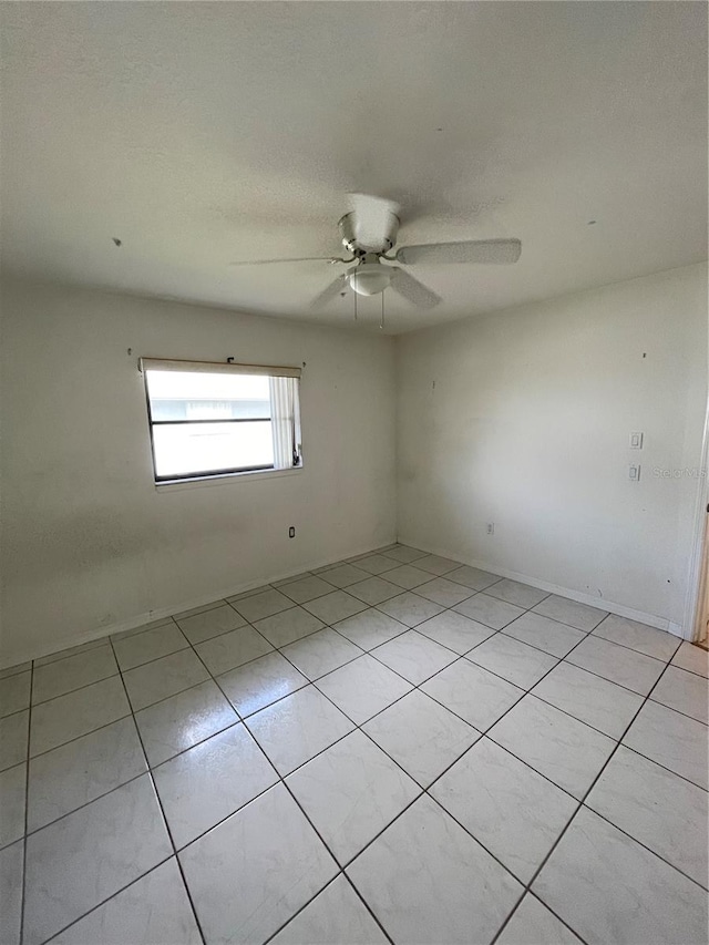 tiled spare room featuring ceiling fan