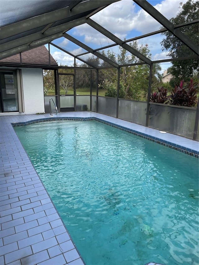 view of swimming pool featuring glass enclosure