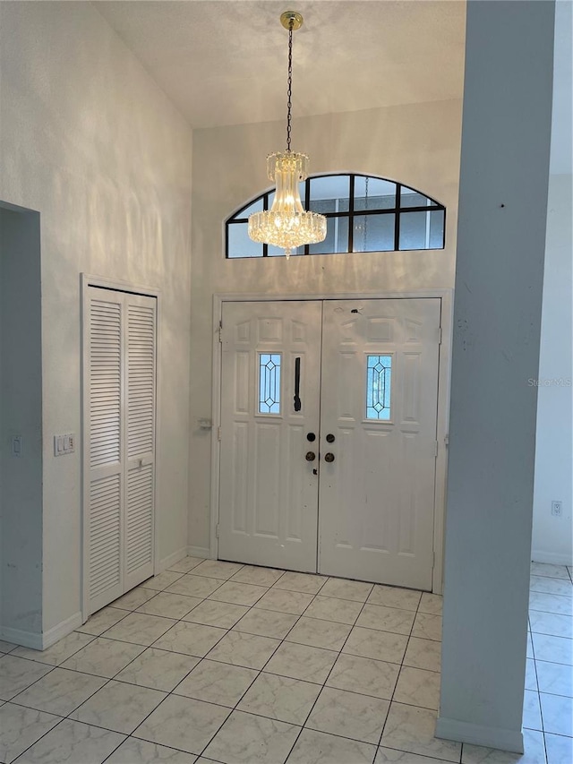 entryway featuring a towering ceiling, a notable chandelier, and light tile patterned floors