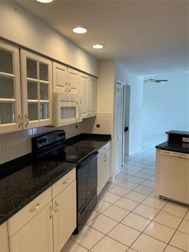 kitchen with white cabinets, ceiling fan, light tile patterned floors, dark stone counters, and white appliances