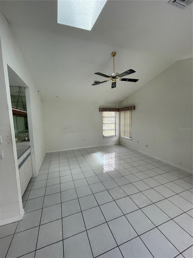 spare room featuring lofted ceiling with skylight, ceiling fan, and light tile patterned floors