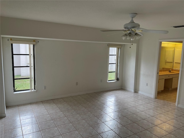 tiled spare room featuring sink and ceiling fan