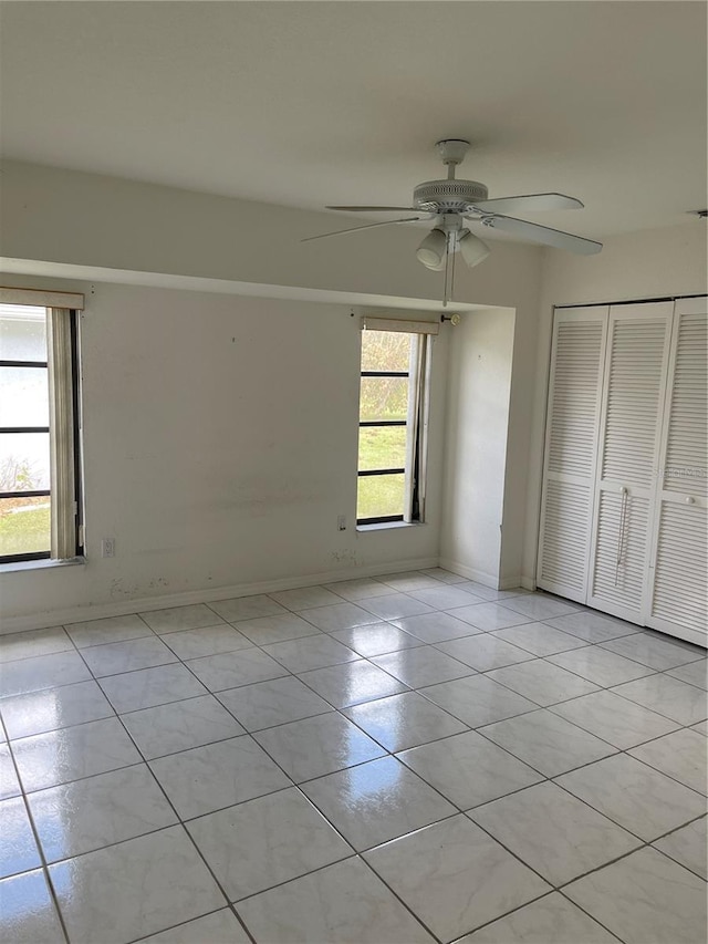 unfurnished bedroom featuring light tile patterned floors, multiple windows, a closet, and ceiling fan