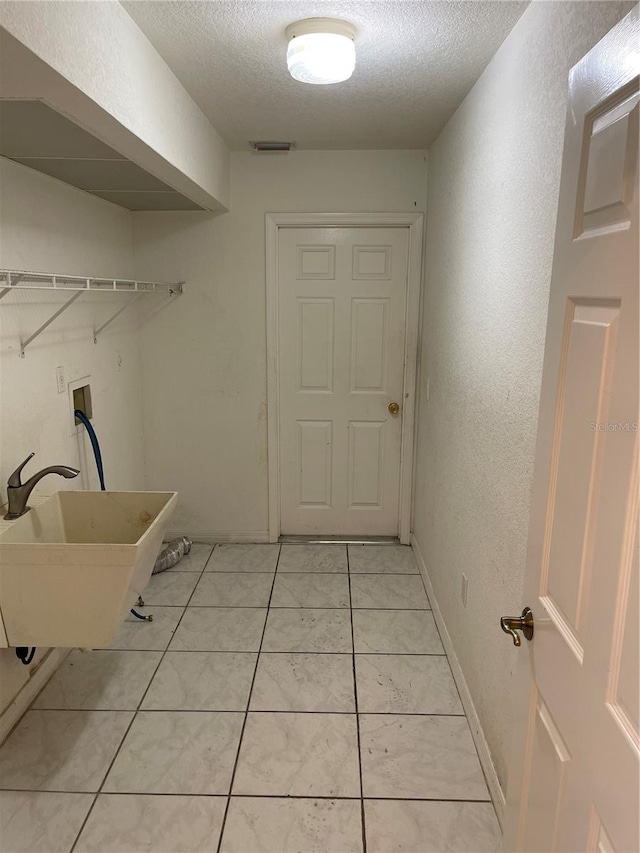 laundry room with sink, a textured ceiling, and light tile patterned floors