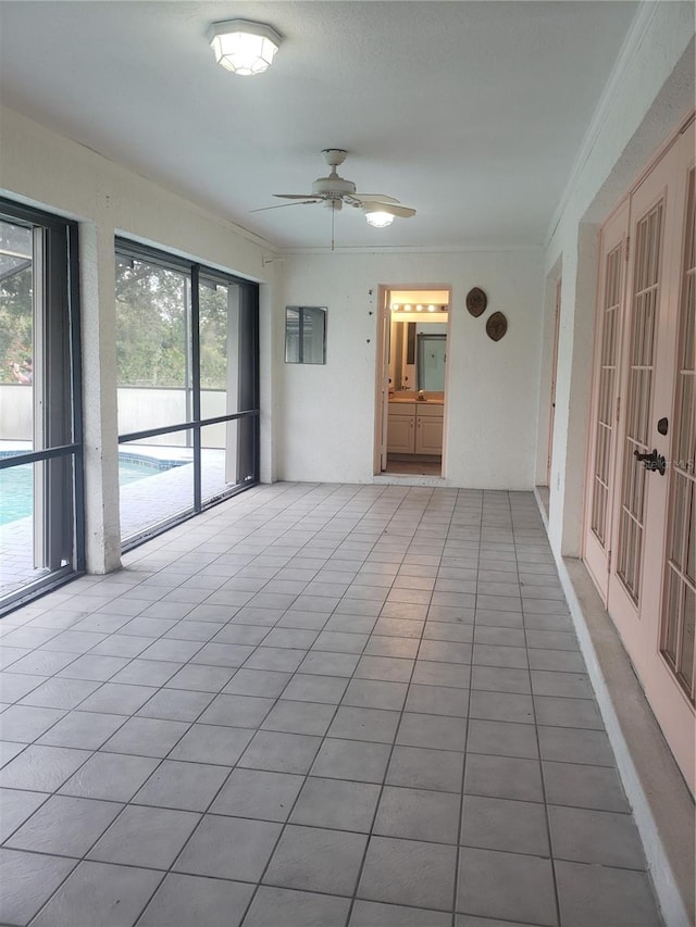 unfurnished sunroom featuring ceiling fan