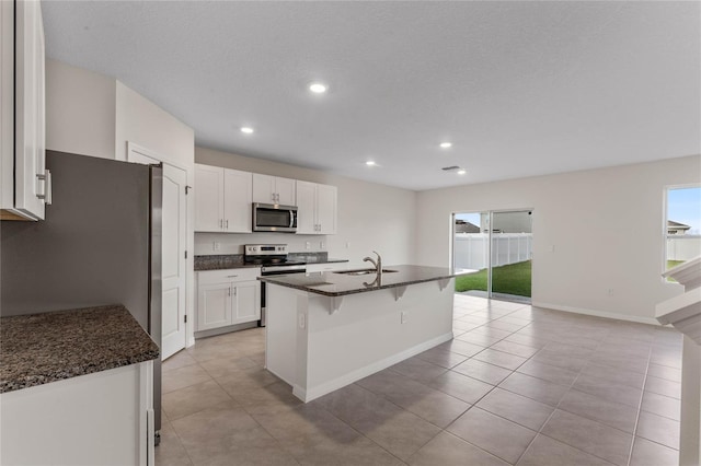 kitchen featuring sink, a kitchen island with sink, stainless steel appliances, a kitchen breakfast bar, and white cabinets