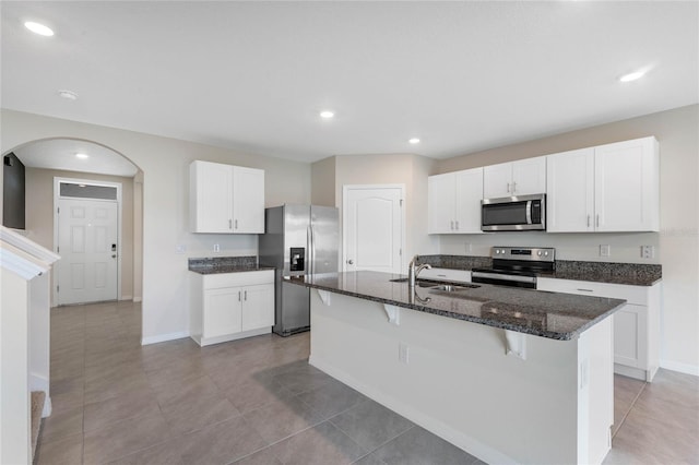 kitchen with a kitchen bar, sink, white cabinetry, a center island with sink, and stainless steel appliances