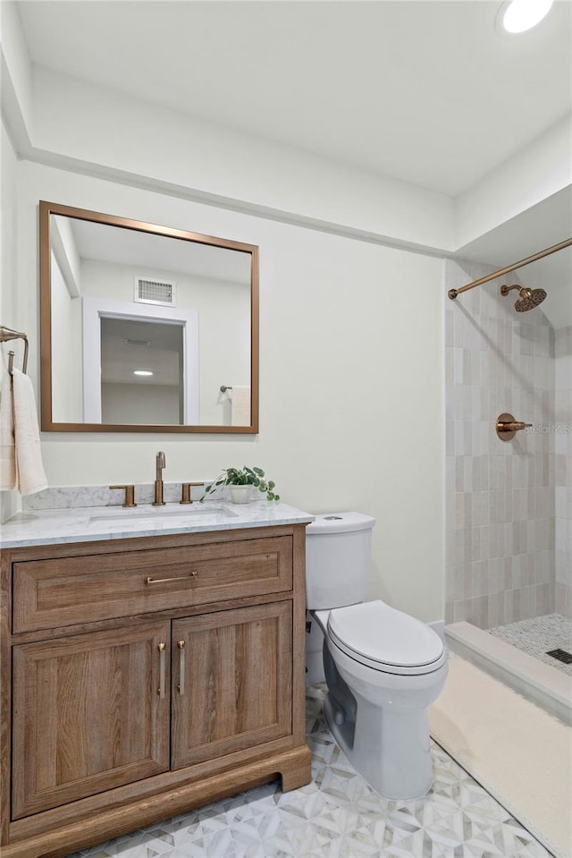 bathroom featuring vanity, toilet, and a tile shower