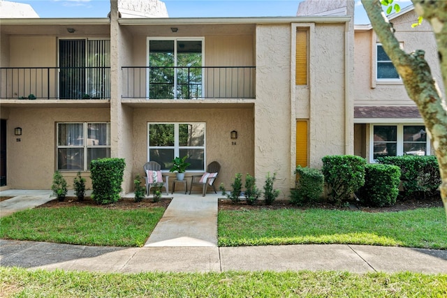 townhome / multi-family property with a patio area, a balcony, and a front lawn