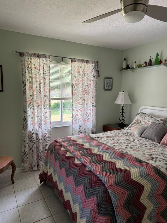 tiled bedroom with ceiling fan and a textured ceiling