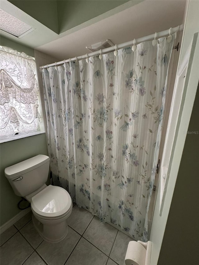 bathroom featuring a shower with shower curtain, tile patterned floors, toilet, and a skylight